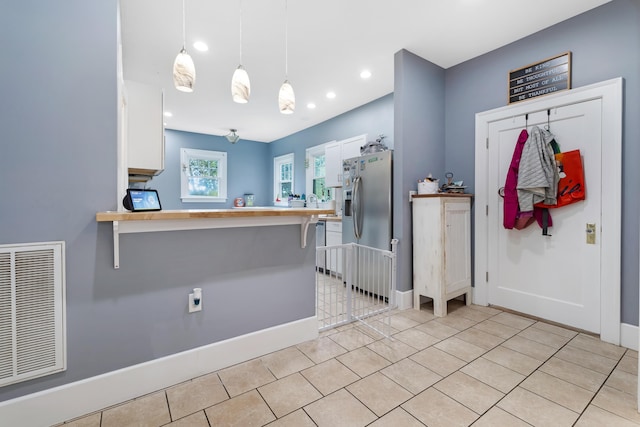 kitchen featuring a breakfast bar, white cabinets, hanging light fixtures, kitchen peninsula, and stainless steel fridge with ice dispenser