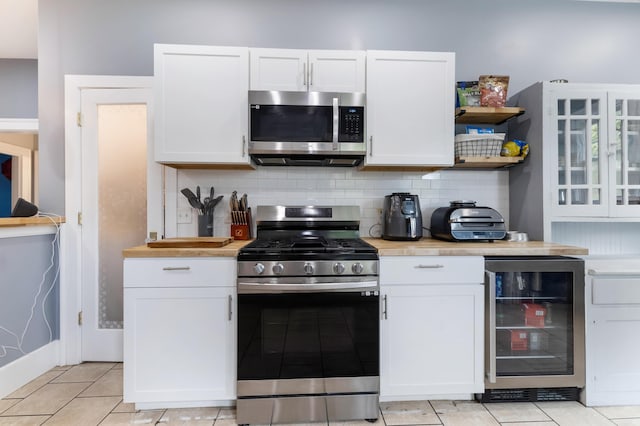 kitchen featuring tasteful backsplash, stainless steel appliances, beverage cooler, light tile patterned floors, and white cabinets