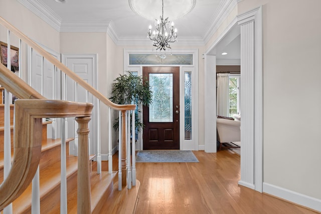 foyer entrance featuring light hardwood / wood-style flooring, ornamental molding, and a notable chandelier