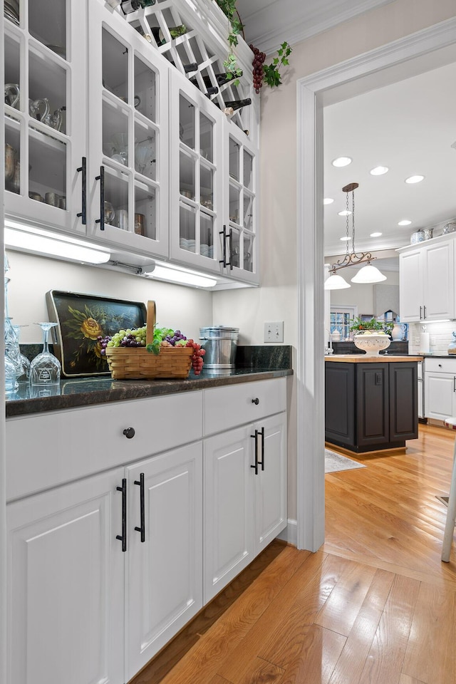 bar featuring white cabinetry, ornamental molding, decorative light fixtures, and light wood-type flooring