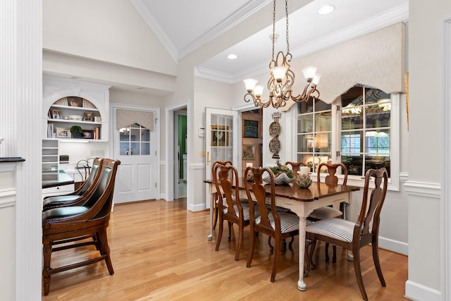 dining area featuring built in shelves, an inviting chandelier, light hardwood / wood-style flooring, crown molding, and lofted ceiling