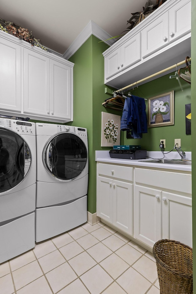 laundry room featuring cabinets, ornamental molding, sink, light tile patterned floors, and washing machine and dryer