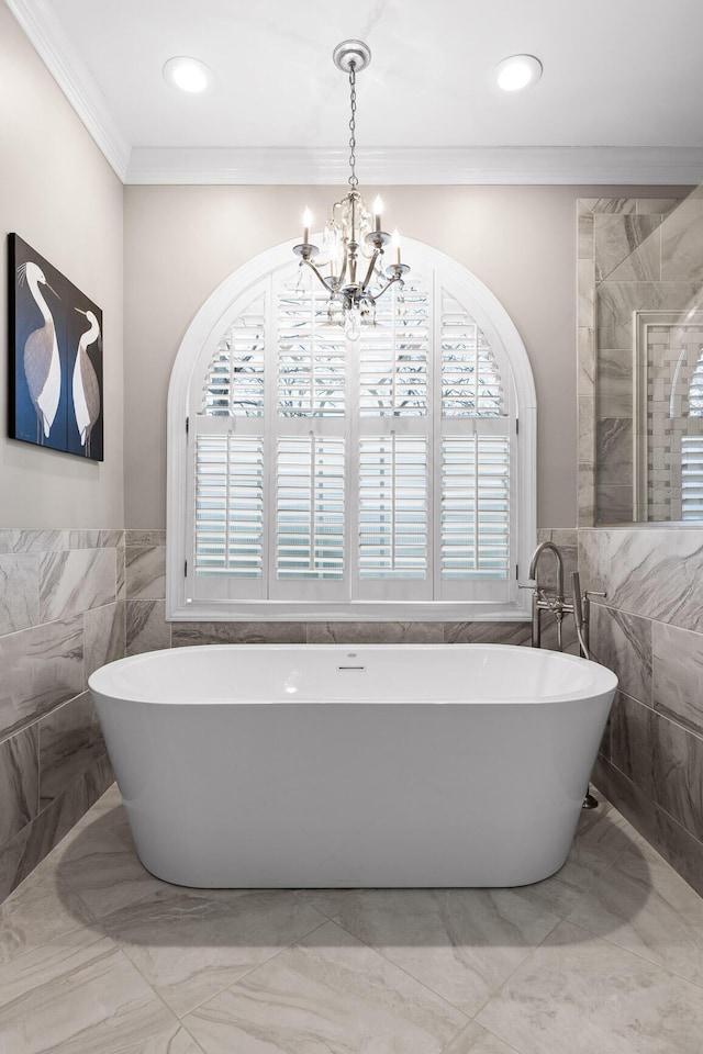 bathroom with a bath, tile walls, ornamental molding, and a notable chandelier