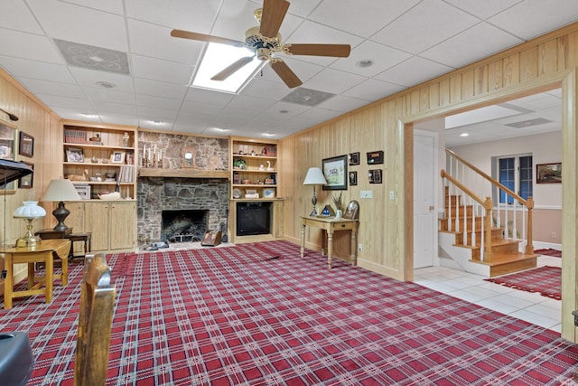 living room with a fireplace, built in shelves, and wood walls