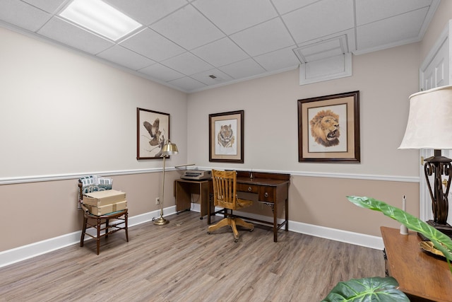 home office with a drop ceiling, crown molding, and light hardwood / wood-style flooring