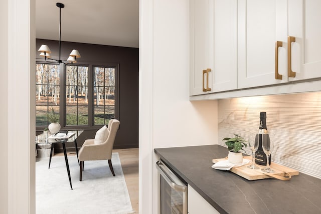 interior space with white cabinets, pendant lighting, and wine cooler