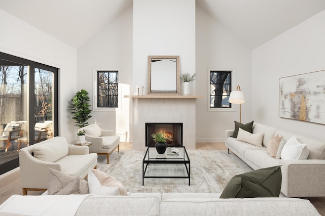 living room with a tile fireplace, hardwood / wood-style floors, and high vaulted ceiling