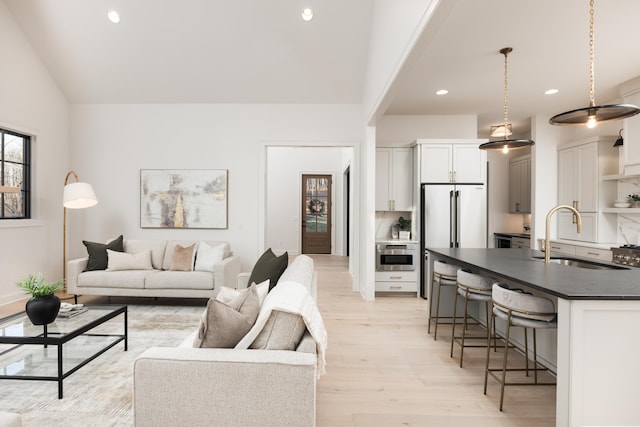 living room with sink, light hardwood / wood-style floors, and lofted ceiling