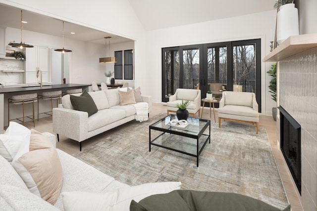 living room with light hardwood / wood-style flooring, french doors, sink, and vaulted ceiling