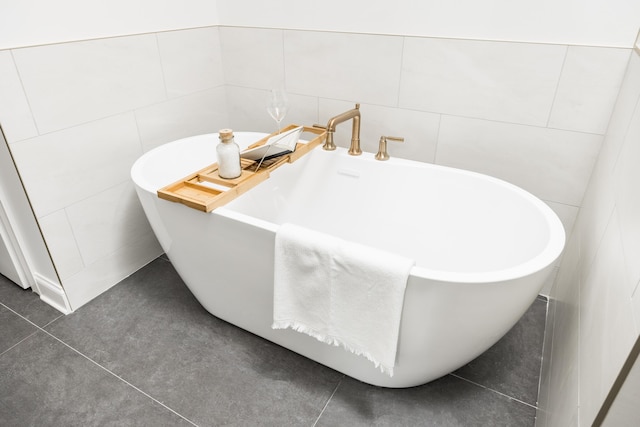 bathroom with tile patterned floors and a washtub