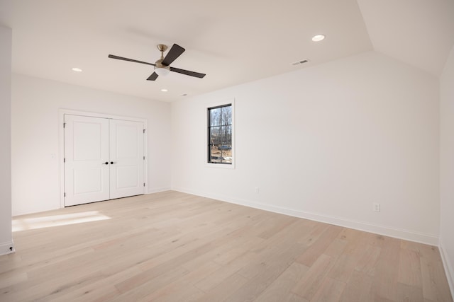 unfurnished bedroom with ceiling fan, a closet, lofted ceiling, and light hardwood / wood-style flooring