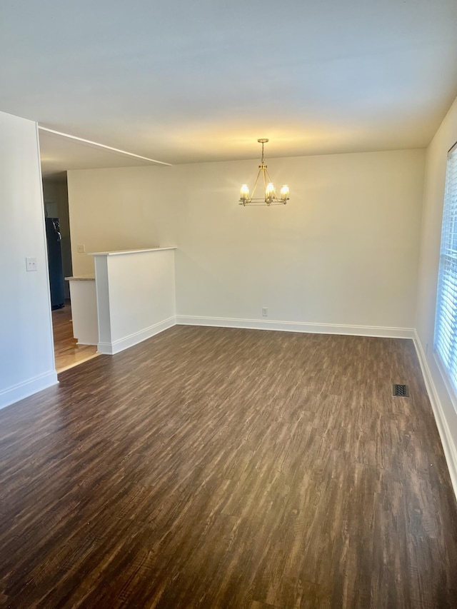 unfurnished room featuring dark hardwood / wood-style flooring and a notable chandelier