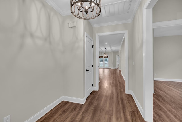 hallway featuring dark wood-type flooring, crown molding, and a notable chandelier