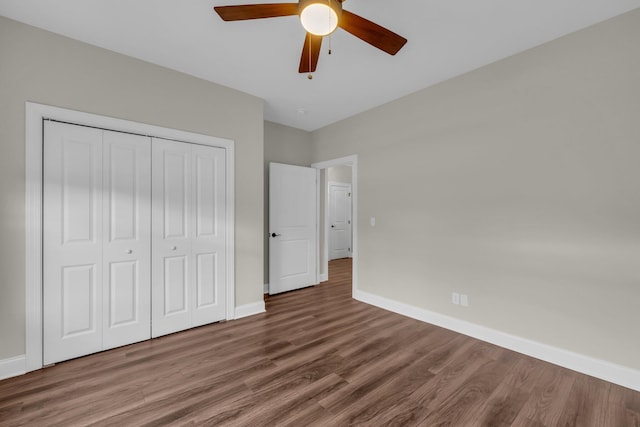 unfurnished bedroom with dark hardwood / wood-style flooring, ceiling fan, and a closet