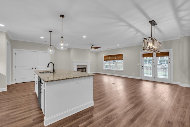 kitchen featuring pendant lighting, a center island with sink, white cabinetry, and sink