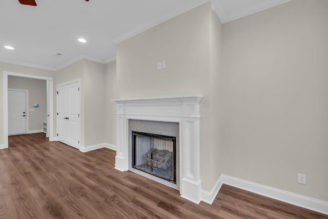 unfurnished living room with hardwood / wood-style flooring, a brick fireplace, ceiling fan, and ornamental molding