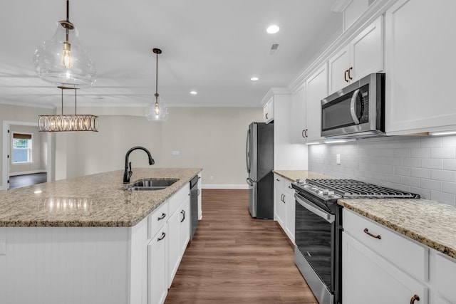 kitchen featuring appliances with stainless steel finishes, a kitchen island with sink, sink, white cabinets, and hanging light fixtures