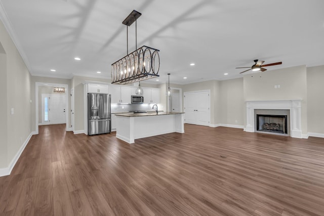 unfurnished living room with ceiling fan, sink, dark wood-type flooring, and ornamental molding