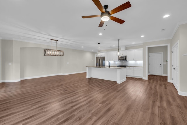 unfurnished living room with ceiling fan, ornamental molding, sink, and dark wood-type flooring