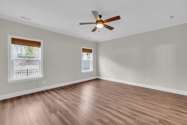 spare room with ceiling fan, ornamental molding, a healthy amount of sunlight, and light wood-type flooring