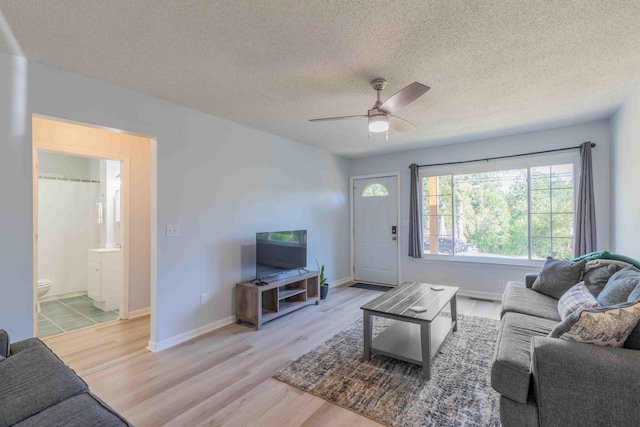 living room with a textured ceiling, light hardwood / wood-style floors, and ceiling fan