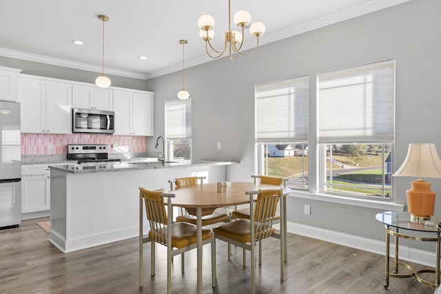 dining room with dark hardwood / wood-style flooring, ornamental molding, sink, and a chandelier