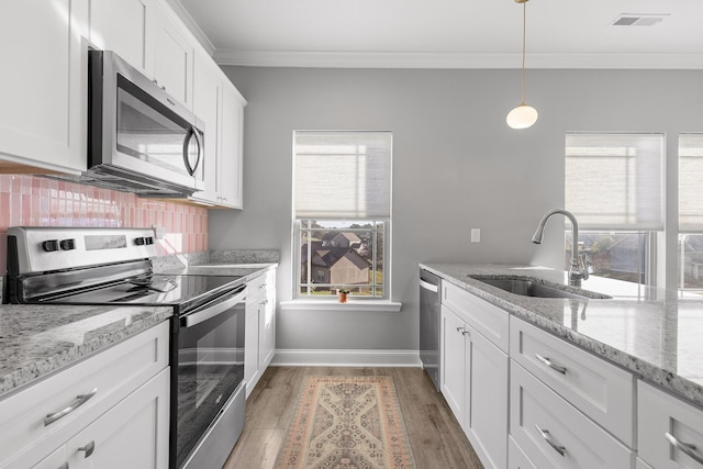 kitchen with light stone counters, stainless steel appliances, sink, decorative light fixtures, and white cabinets