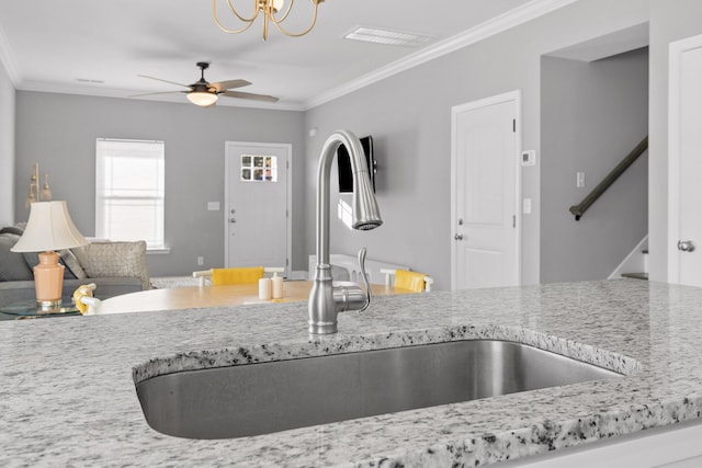 kitchen featuring light stone counters, crown molding, and sink