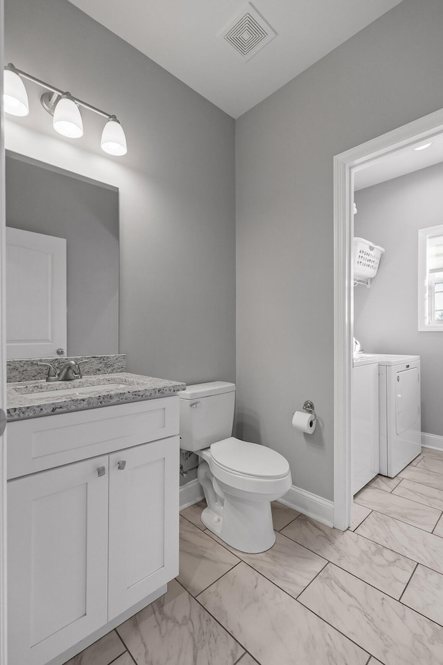 bathroom featuring vanity, separate washer and dryer, and toilet