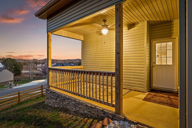 deck at dusk featuring ceiling fan