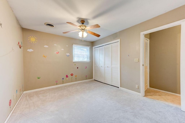 unfurnished bedroom featuring ceiling fan, a closet, and light colored carpet