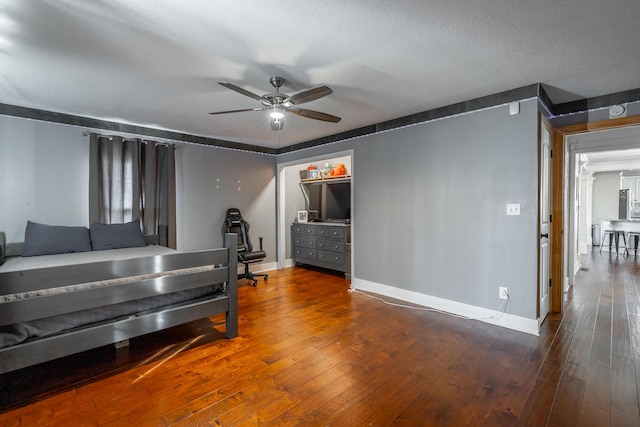 bedroom featuring ceiling fan, wood-type flooring, and a textured ceiling