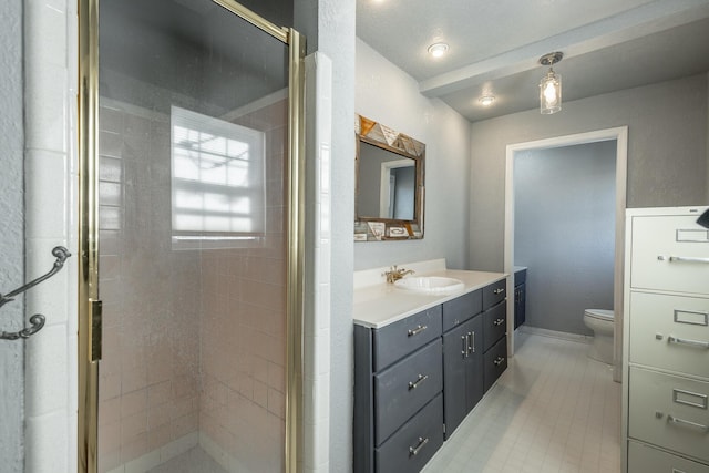 bathroom with toilet, a shower with shower door, and vanity