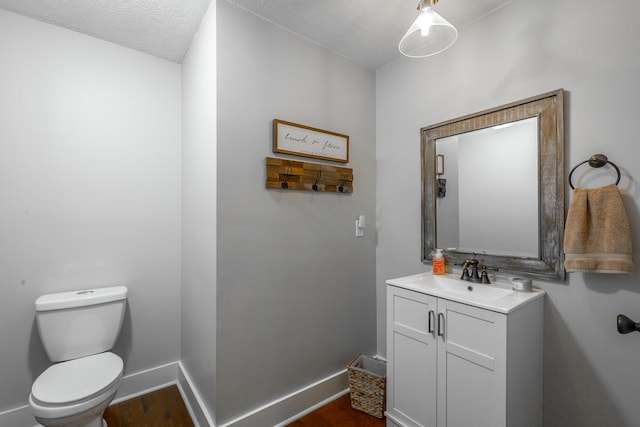 bathroom featuring a textured ceiling, toilet, wood-type flooring, and vanity