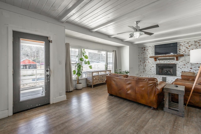 living room with ceiling fan, a fireplace, beamed ceiling, and hardwood / wood-style floors