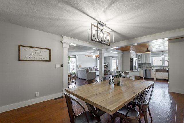 dining room featuring ceiling fan with notable chandelier, a textured ceiling, dark wood-type flooring, sink, and crown molding