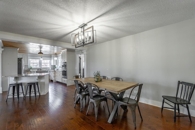 dining space with a textured ceiling, decorative columns, dark hardwood / wood-style floors, and a notable chandelier