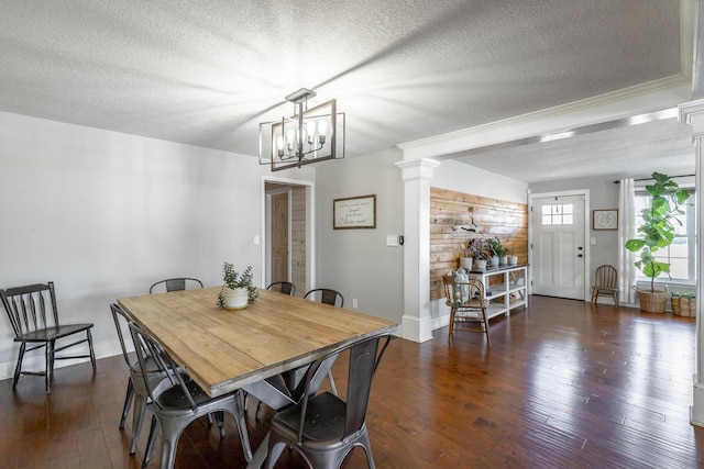 dining area with dark hardwood / wood-style flooring, a notable chandelier, a textured ceiling, and ornate columns