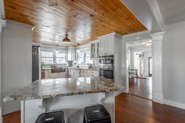 kitchen featuring white cabinetry, wood ceiling, a kitchen bar, dark hardwood / wood-style floors, and sink