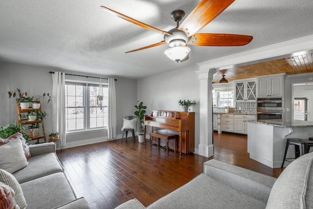 living room featuring decorative columns, wooden ceiling, ceiling fan, dark hardwood / wood-style floors, and a textured ceiling