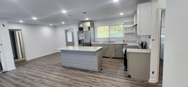 kitchen with sink, hanging light fixtures, stainless steel fridge, a kitchen island, and range