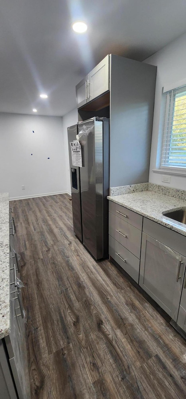 kitchen with stainless steel fridge, dark hardwood / wood-style flooring, light stone counters, gray cabinetry, and sink