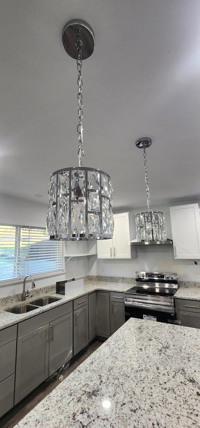 kitchen with sink, white cabinets, pendant lighting, and stainless steel electric range