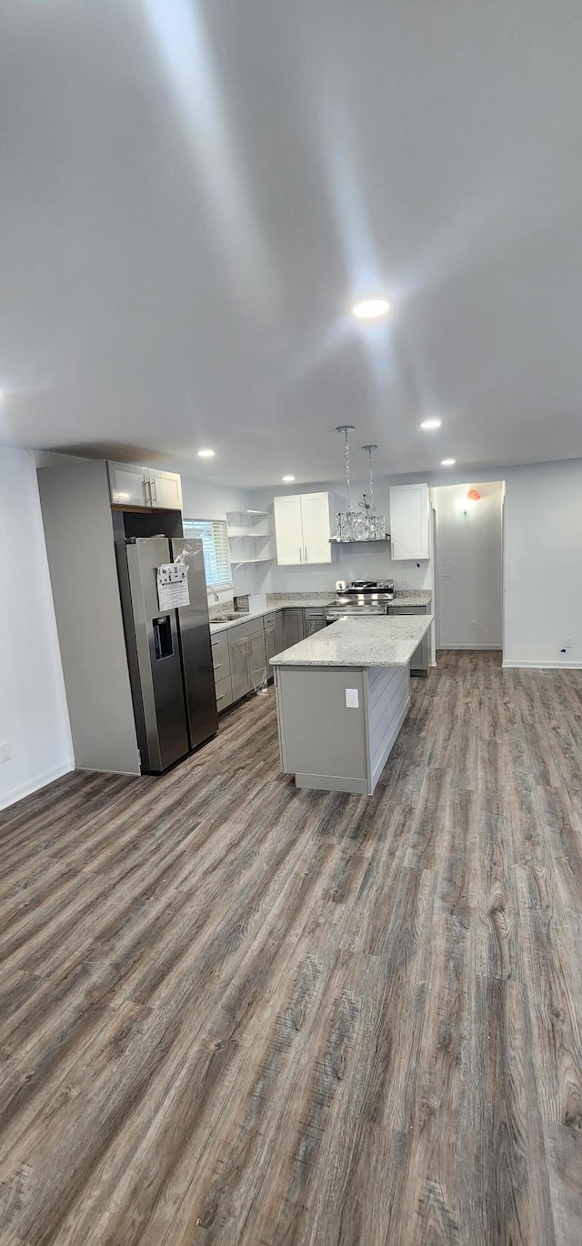 kitchen with a center island, hardwood / wood-style floors, decorative light fixtures, white cabinets, and appliances with stainless steel finishes