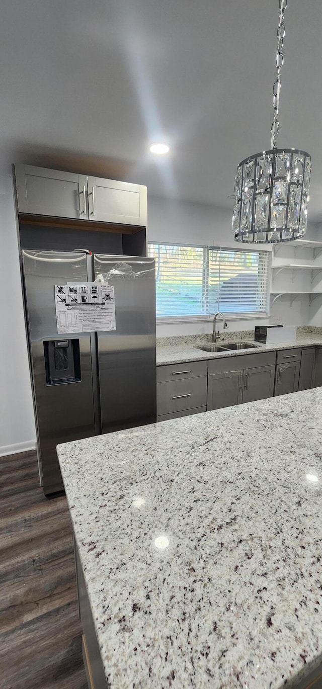 kitchen featuring gray cabinetry, sink, stainless steel refrigerator with ice dispenser, light stone countertops, and decorative light fixtures