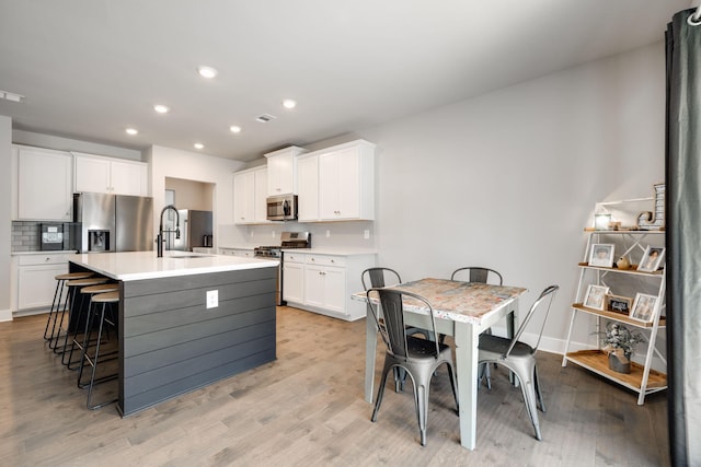 kitchen featuring white cabinets, a center island with sink, and appliances with stainless steel finishes