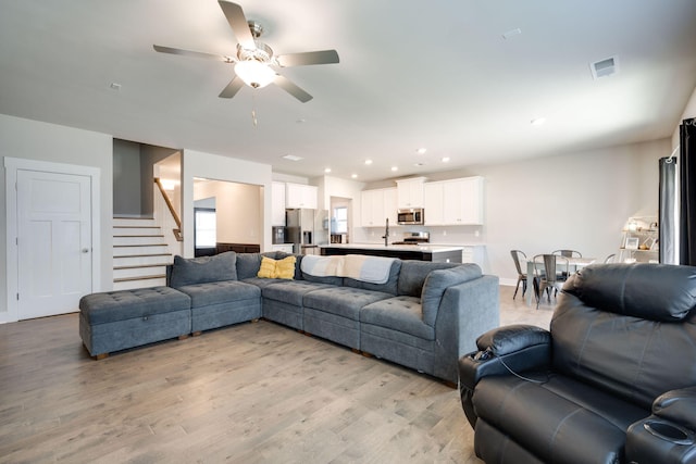 living room featuring light hardwood / wood-style flooring and ceiling fan