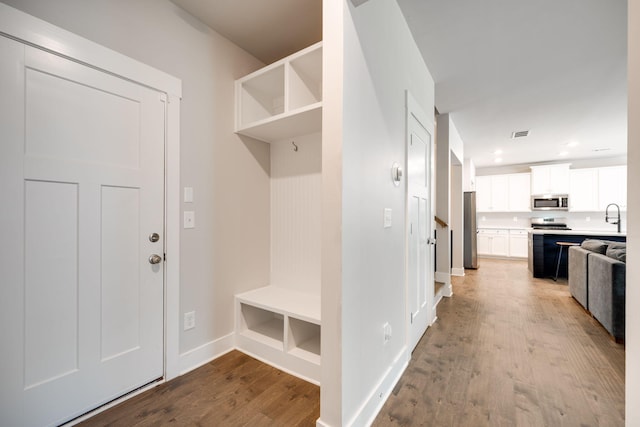 mudroom featuring built in shelves, light wood-type flooring, and sink