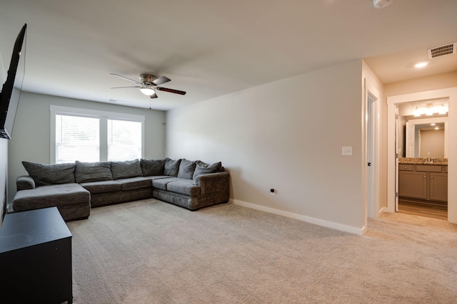 living room with ceiling fan, light colored carpet, and sink