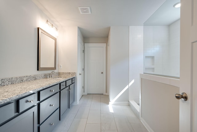 bathroom with tile patterned flooring, vanity, and walk in shower